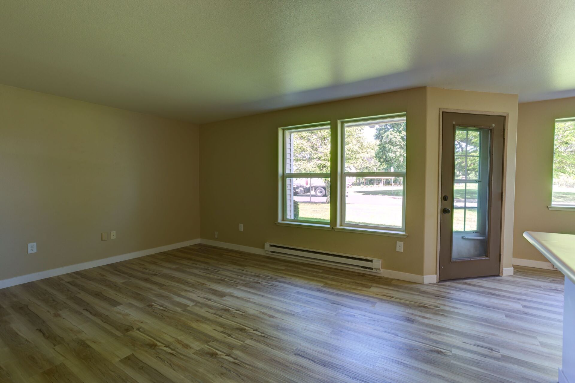 An empty living room with hardwood floors and a sliding glass door.