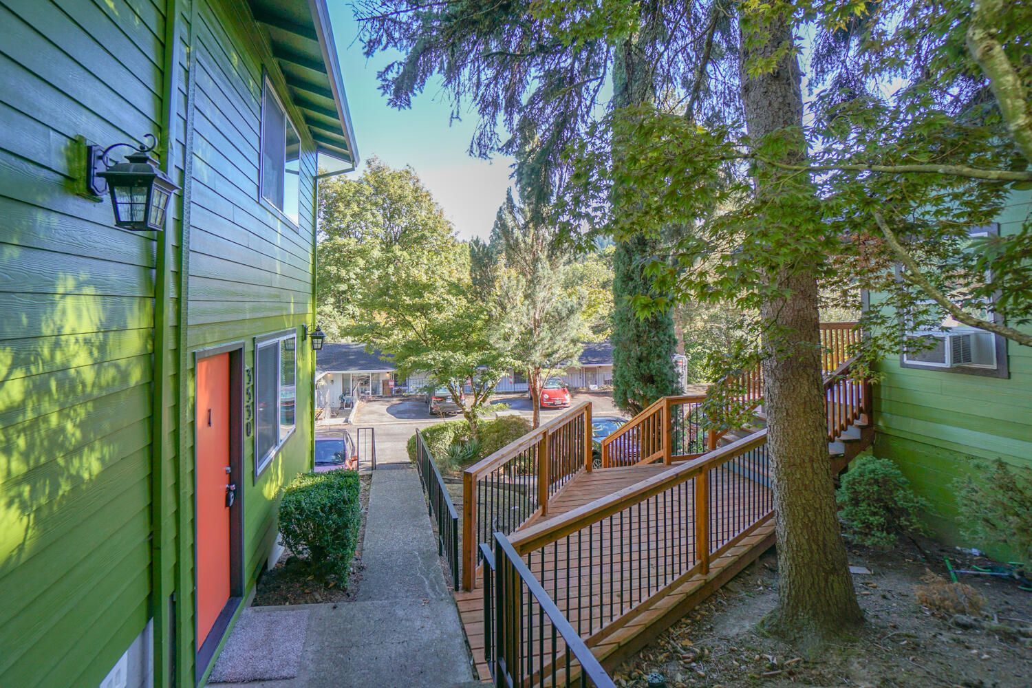 Green apartment buildings with an orange door, connected by a wooden ramp.