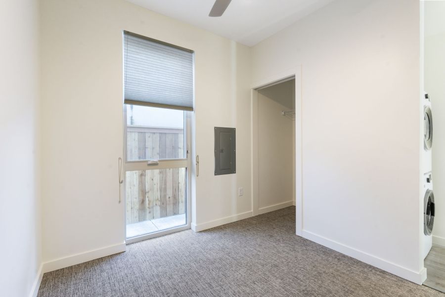 An empty bedroom with a large window and a ceiling fan.