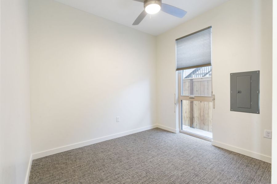An empty bedroom with a ceiling fan and a window.