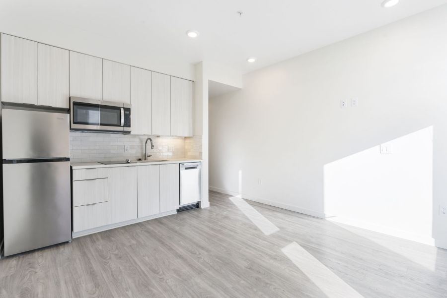 A kitchen with white cabinets , a stainless steel refrigerator , a microwave , and a sink.