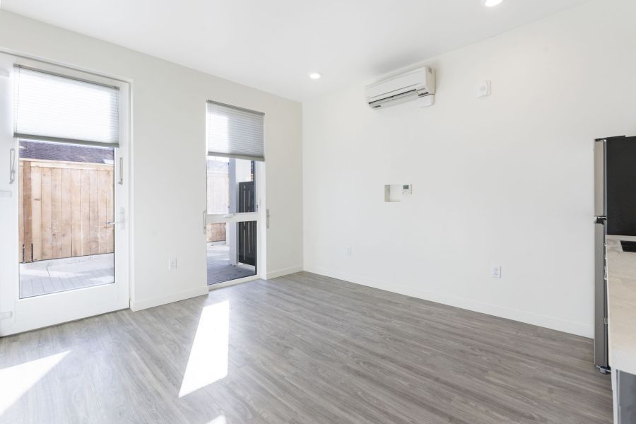 An empty living room with hardwood floors and white walls.