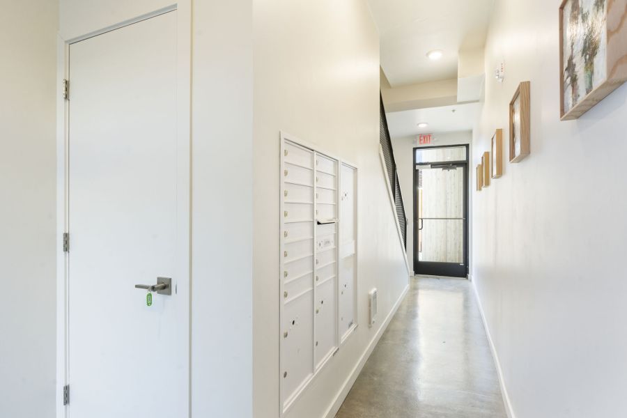 A long hallway with a door and mailboxes on the wall.
