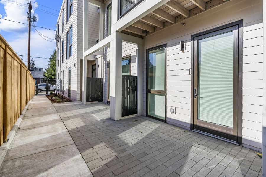 There is a patio in front of a building with sliding glass doors.