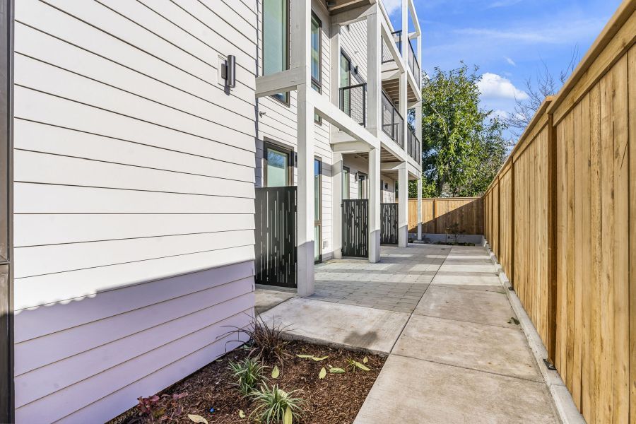 A concrete walkway leading to a building with a wooden fence.