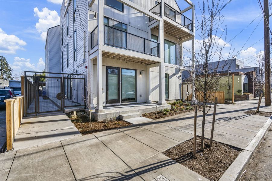 A white building with a lot of windows and balconies is sitting on the side of a street.