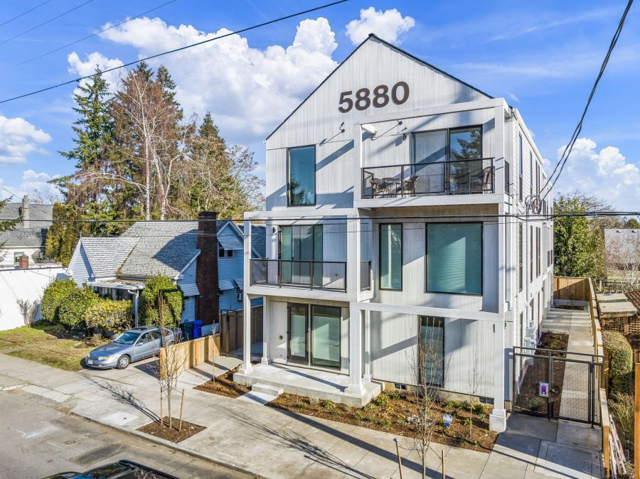 An aerial view of a white apartment building with a car parked in front of it.