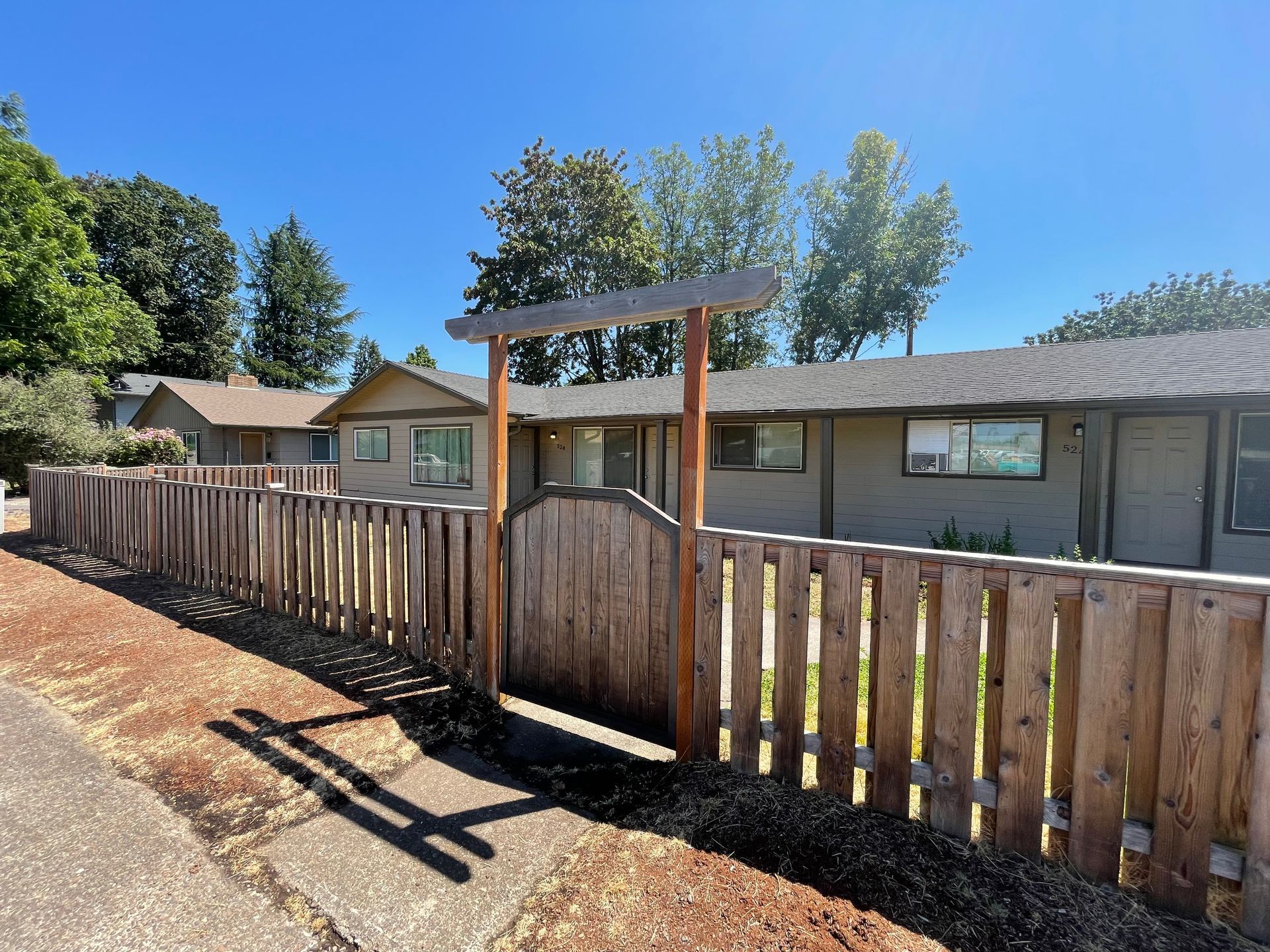 A wooden fence surrounds a house on a sunny day.