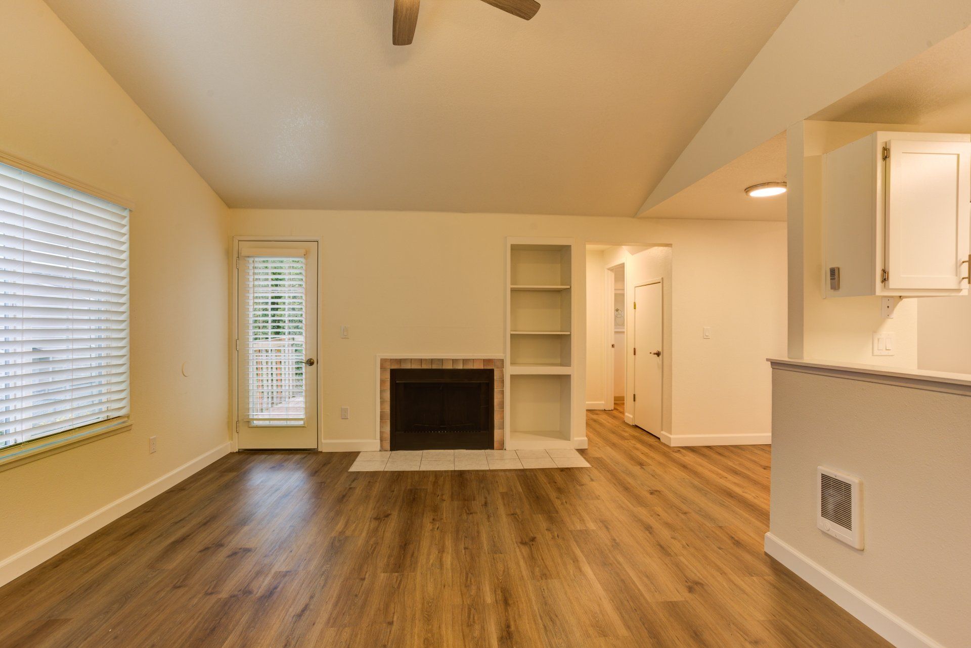 An empty living room with hardwood floors and a fireplace.