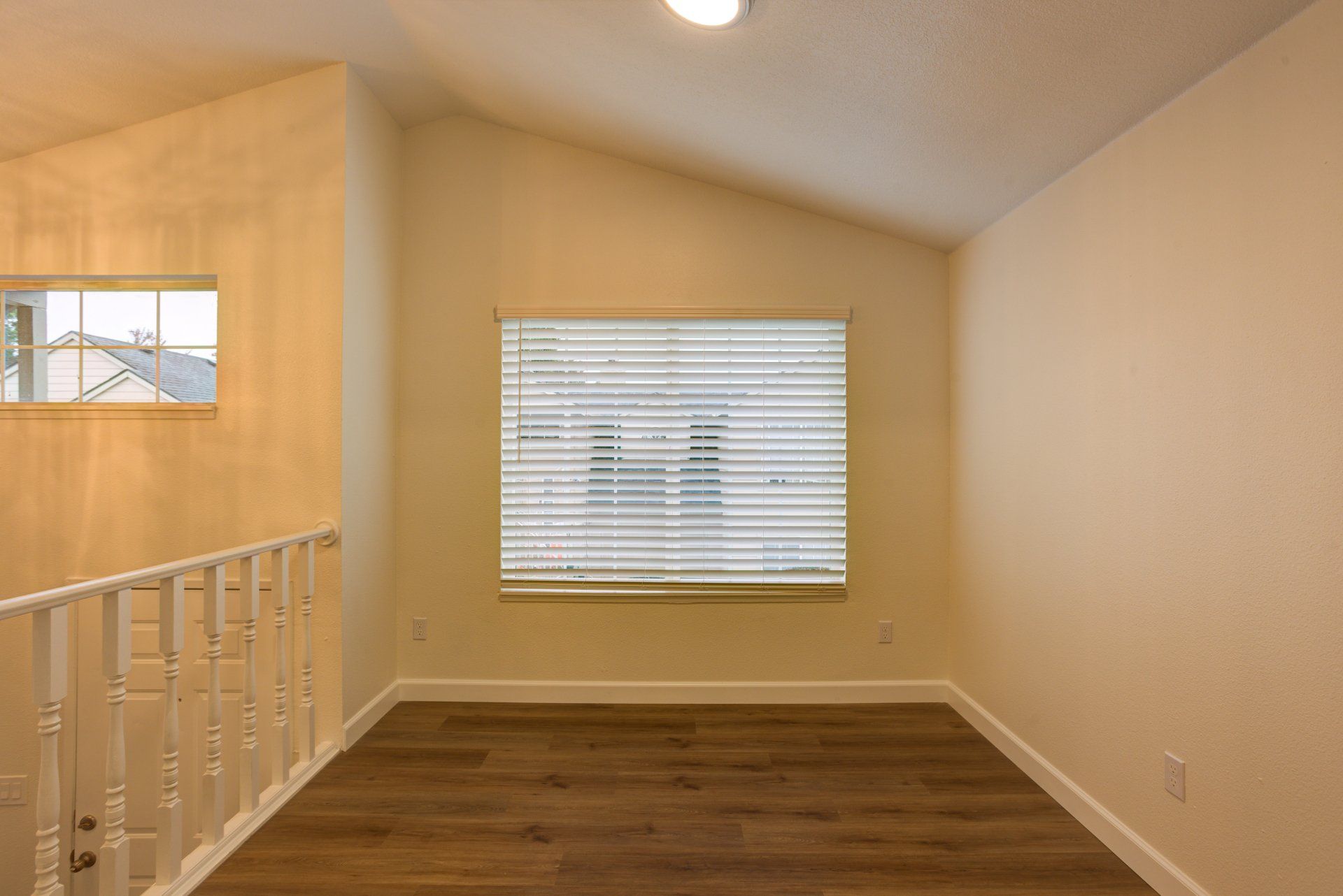 An empty room with hardwood floors and a window.