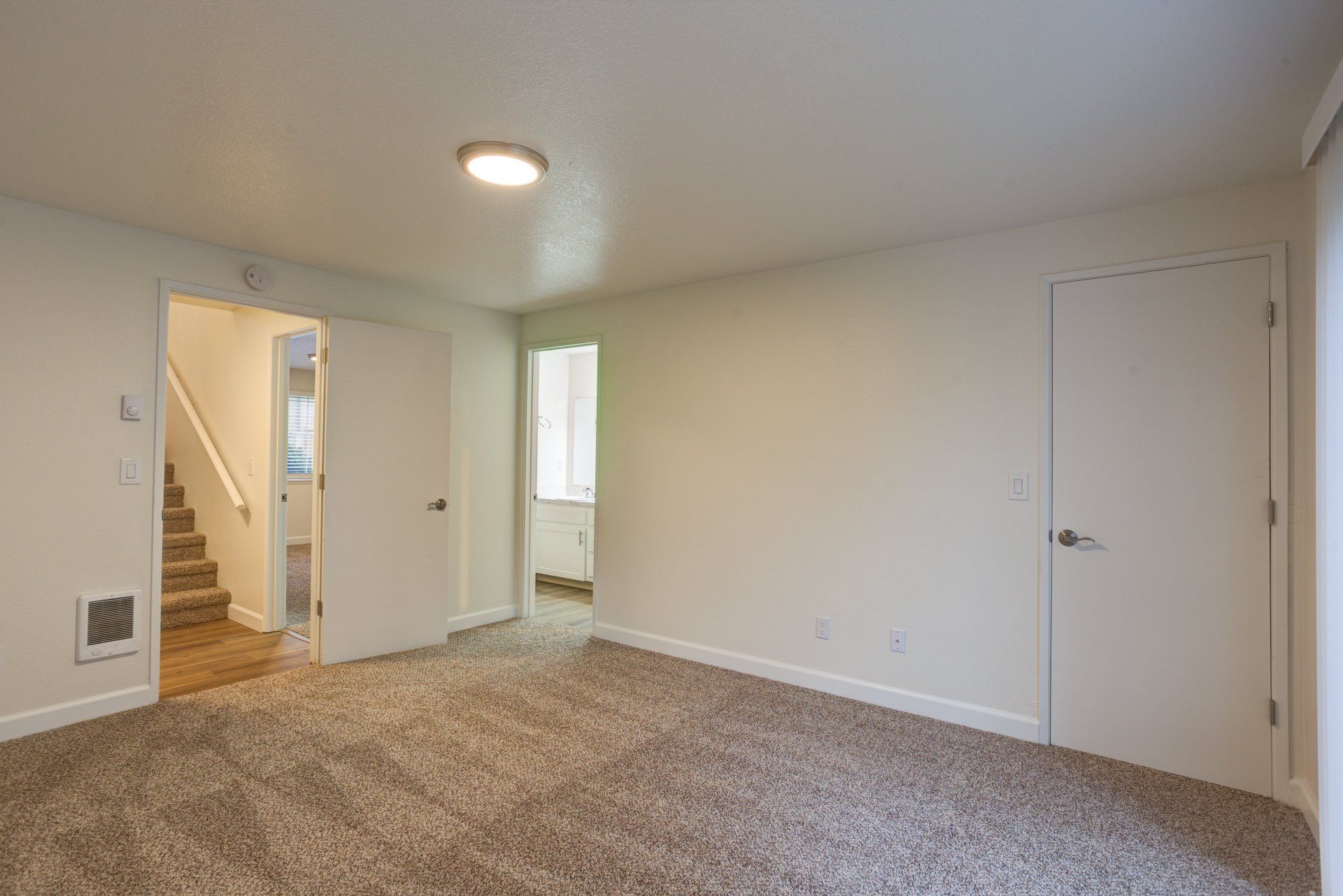 An empty basement with a carpeted floor and white walls.