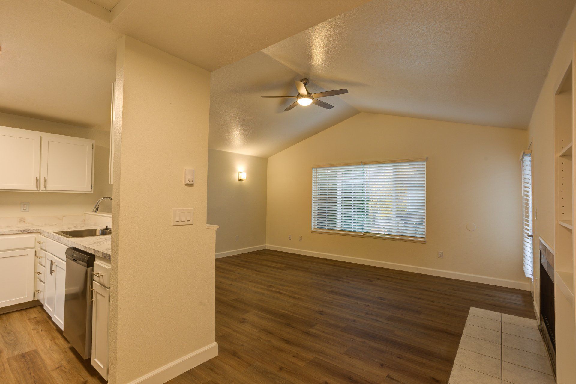 An empty living room with hardwood floors and a ceiling fan.