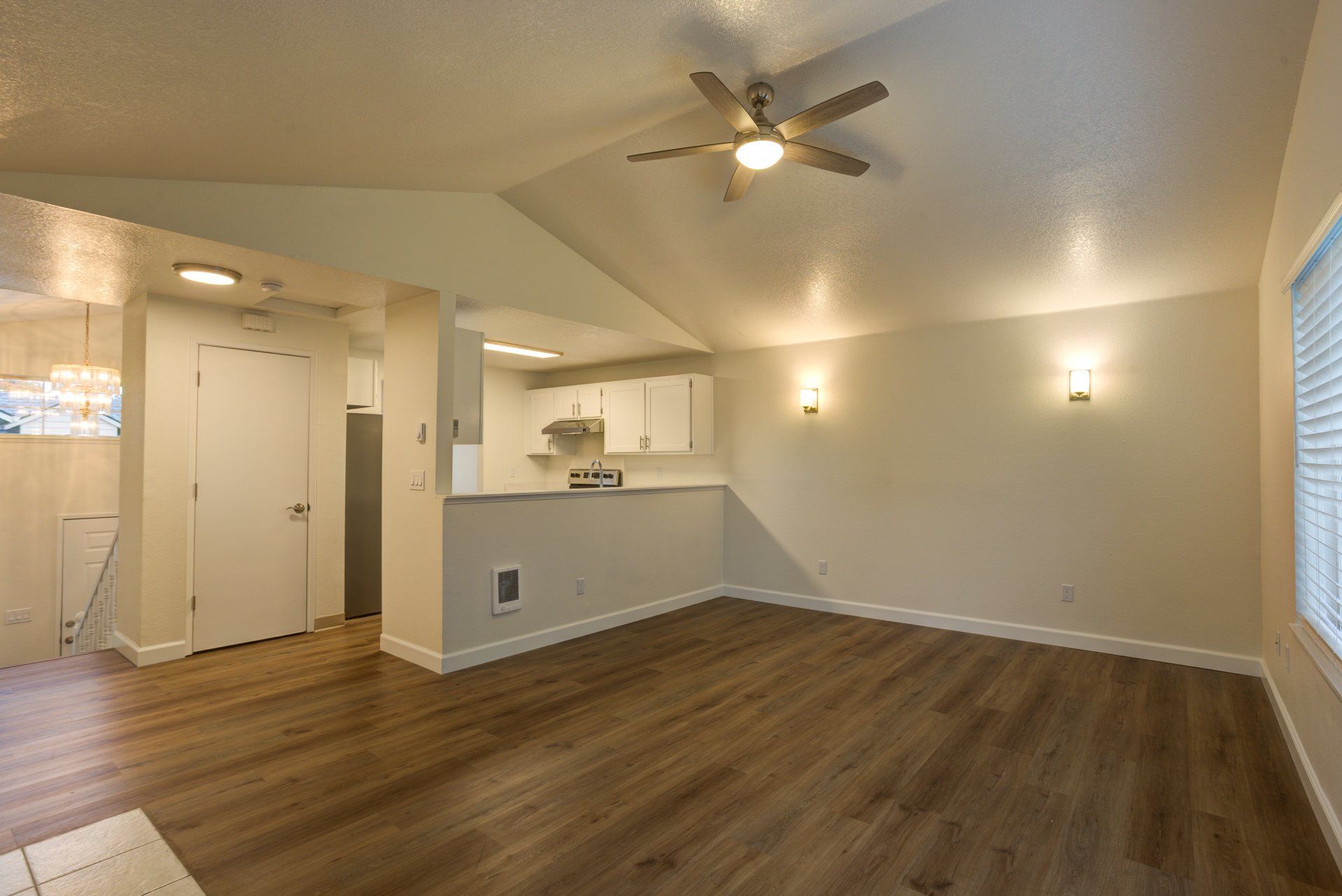 An empty living room with hardwood floors and a ceiling fan.