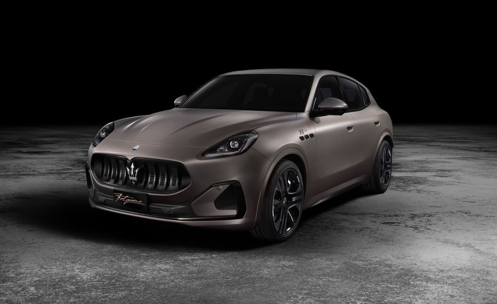 Matte brown luxury sports sedan on a dark studio floor, angled front-left view
