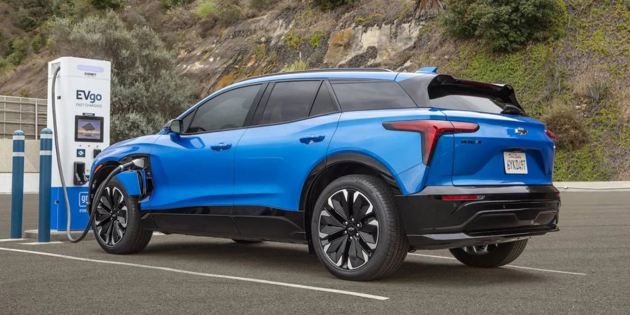 Blue SUV plugged into a charging station on a roadside pullout