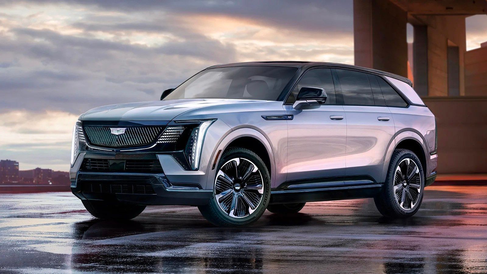 Silver SUV parked on a wet surface at sunset with city skyline in the background