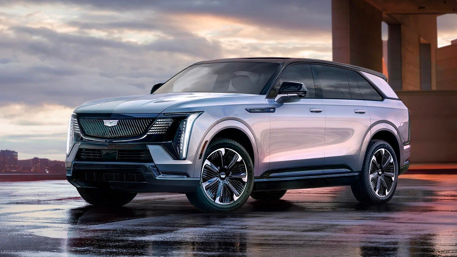 Silver SUV parked on a wet surface at sunset, with a city skyline in the background