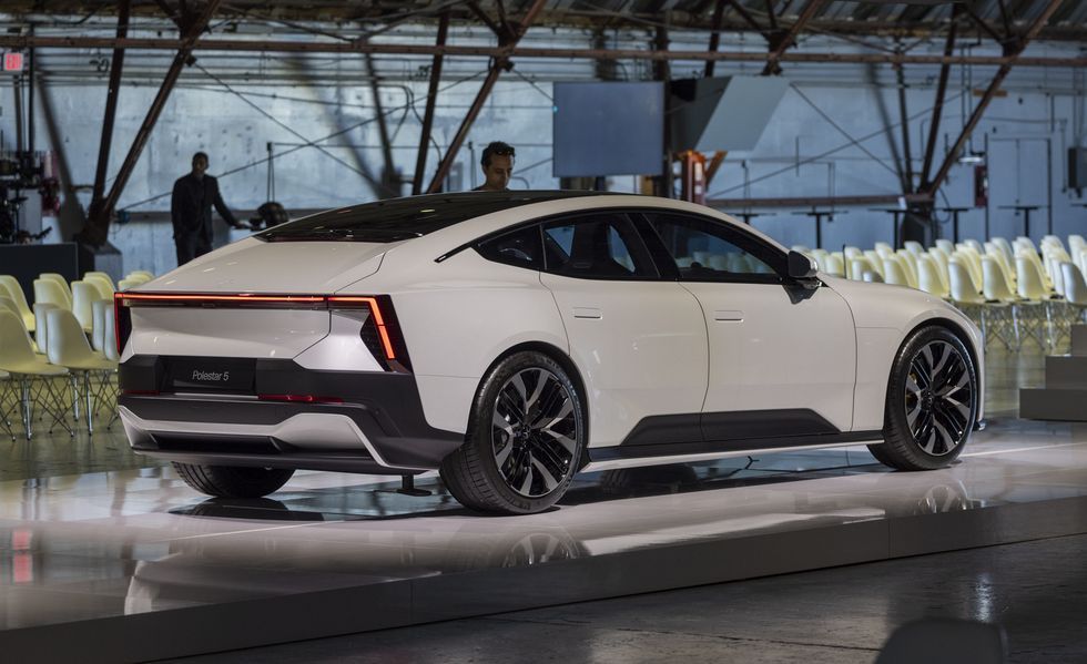White sports car on display in a showroom or event space, viewed from the rear side
