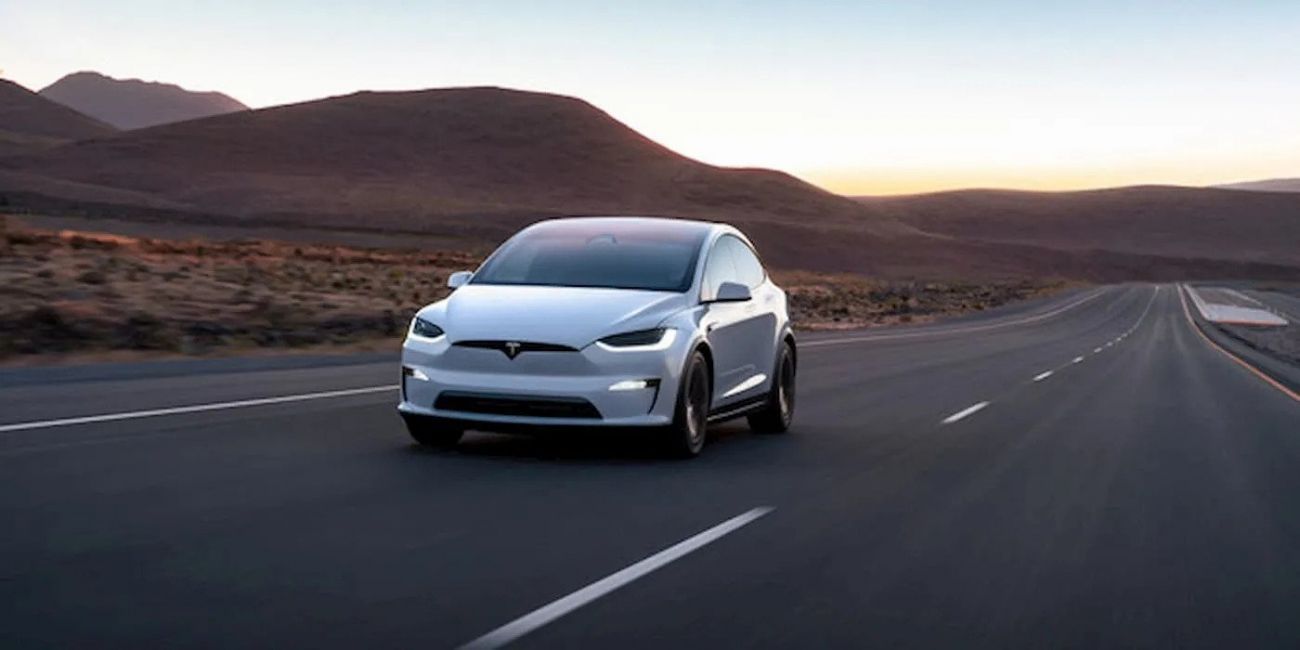 Silver car driving on an open road at sunset with mountains in the background