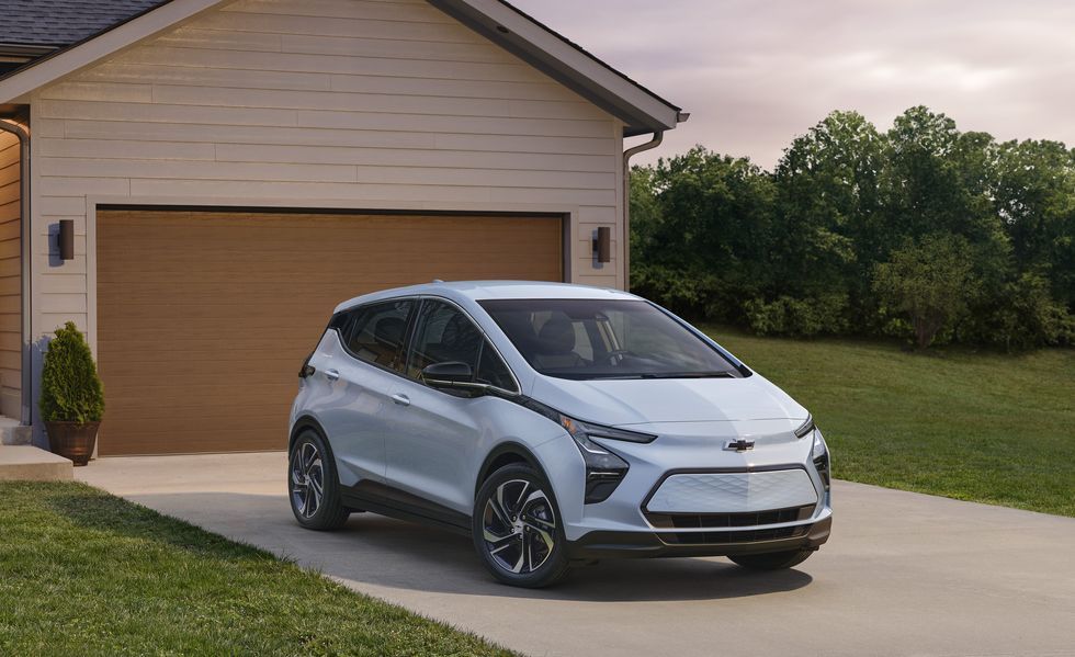 Silver Chevrolet Bolt parked in a driveway in front of a garage at dusk