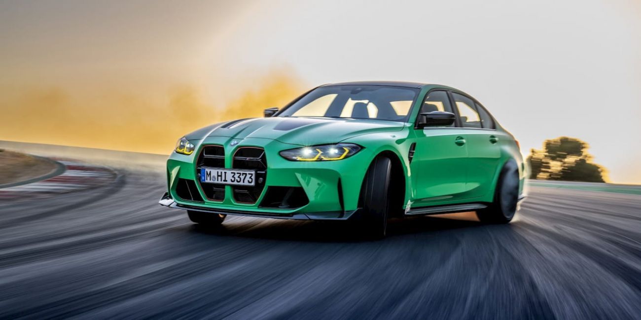 Green sports sedan drifting on a racetrack at sunset, kicking up smoke