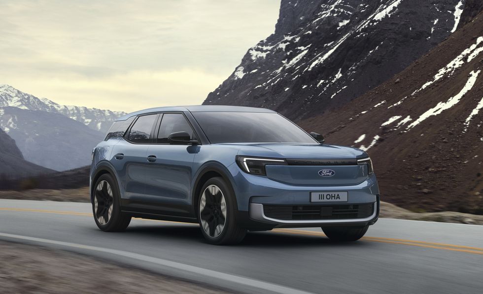 Blue SUV driving on a mountain road with snowy peaks in the background