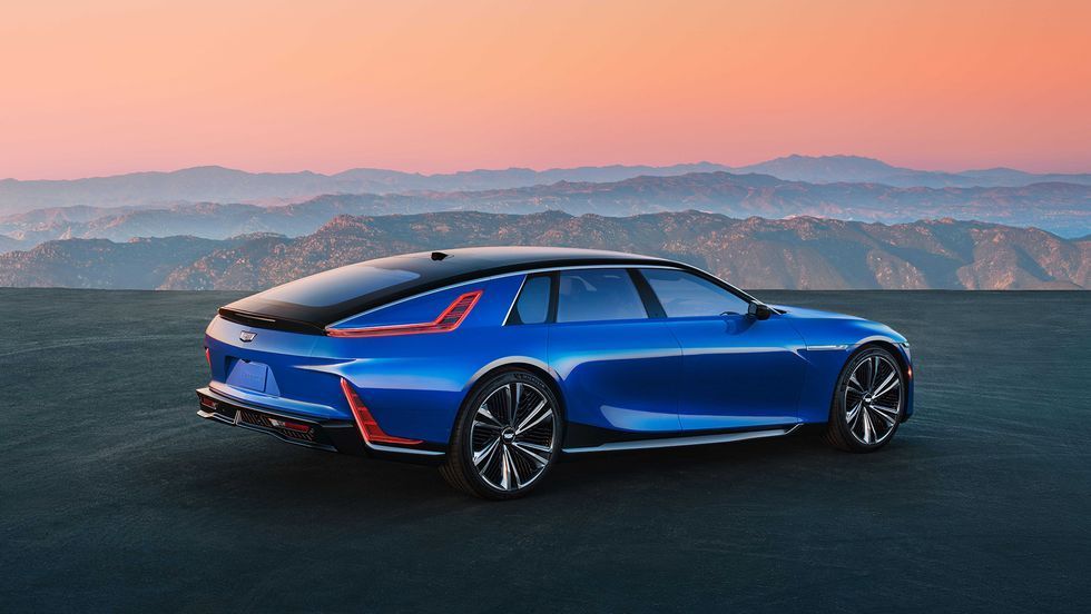 Blue sports sedan parked on a road at sunset with mountains in the background