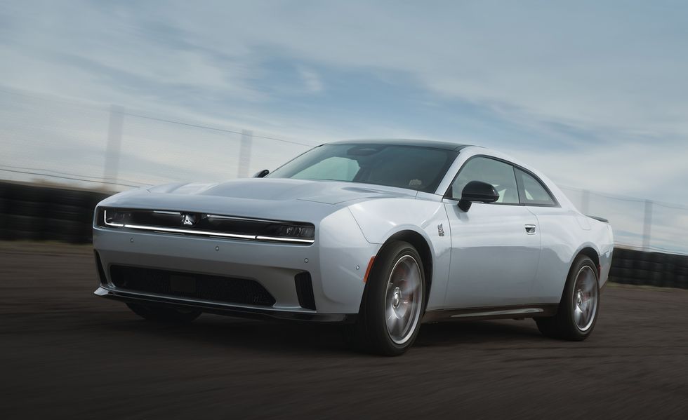 Silver Dodge Challenger driving on a blurred road under a cloudy sky
