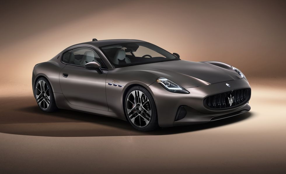 Dark gray sports coupe on a beige studio backdrop, angled front view