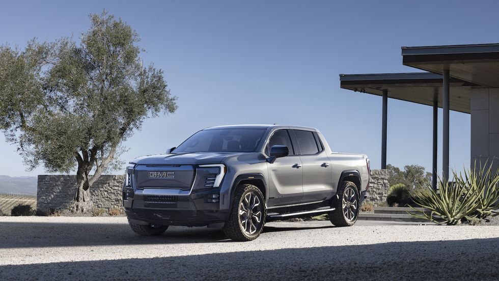 Silver pickup truck parked beside a modern house in a desert landscape