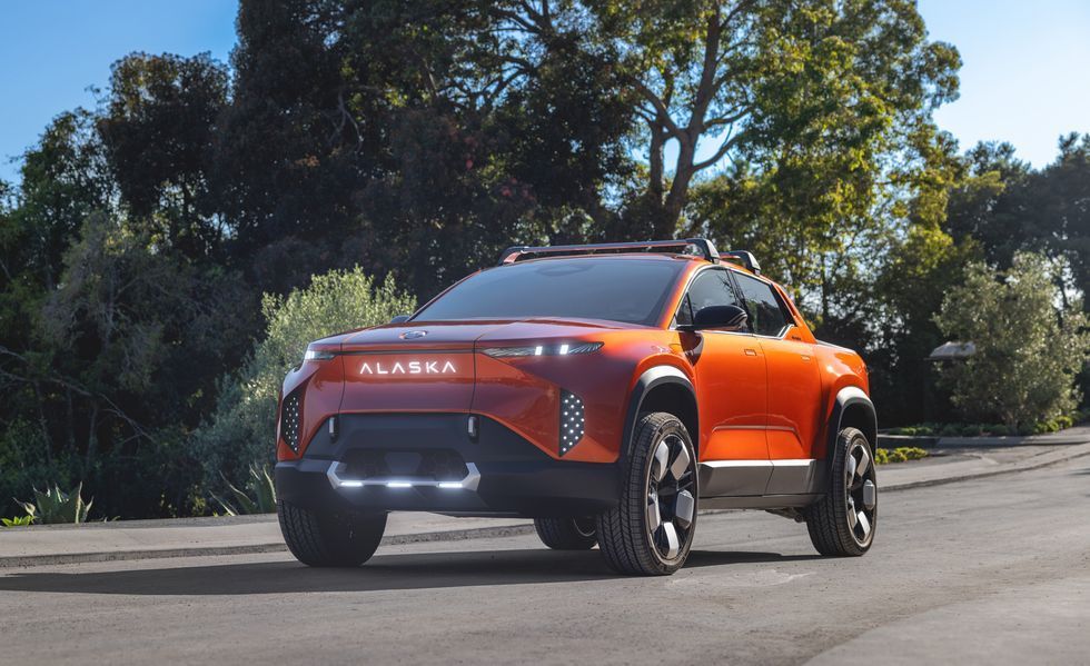 Orange SUV driving on a road, viewed from the front-left with trees in the background