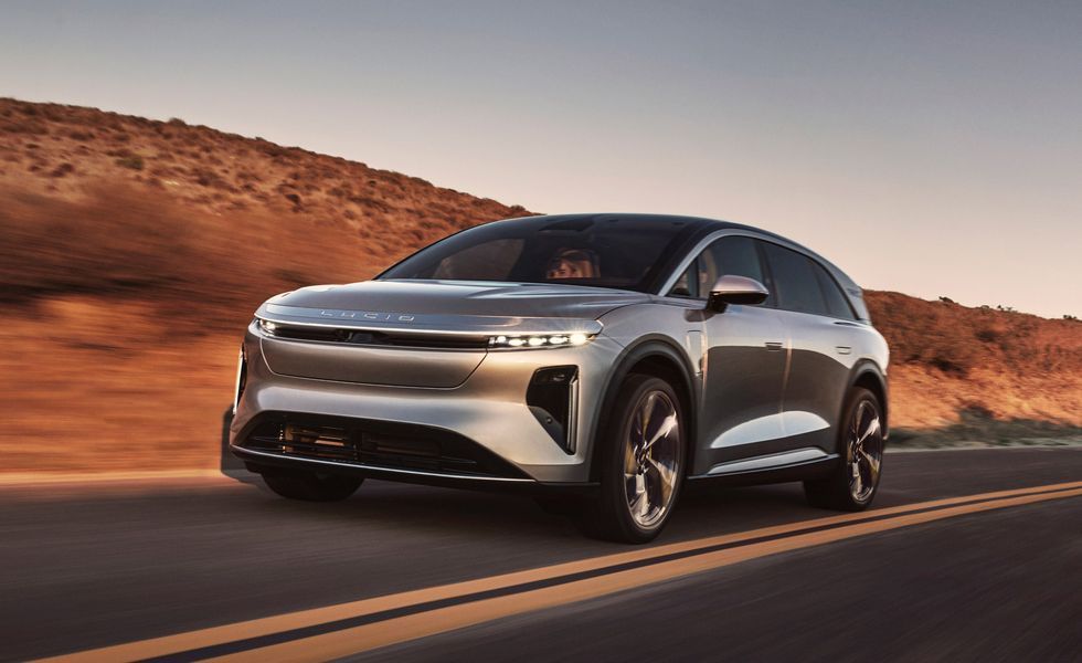 Silver electric SUV driving on a desert highway at sunset