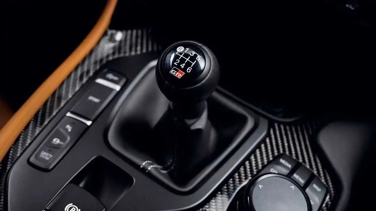 Close-up of a car’s manual gear shift knob and center console in black trim