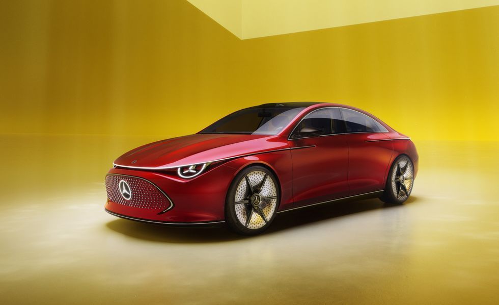 Red concept sedan on a yellow studio backdrop, angled front view with glowing headlights
