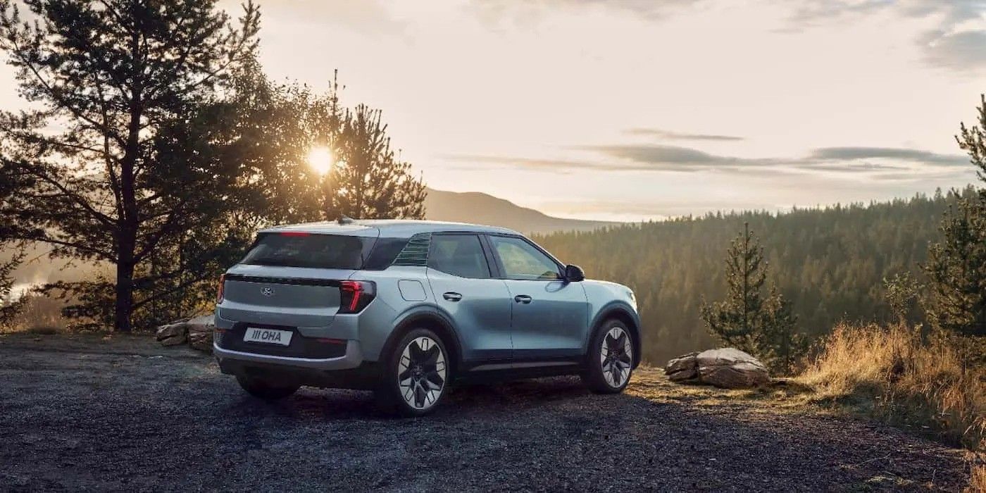 Silver SUV parked on a scenic overlook at sunset with pine trees and mountains in the background