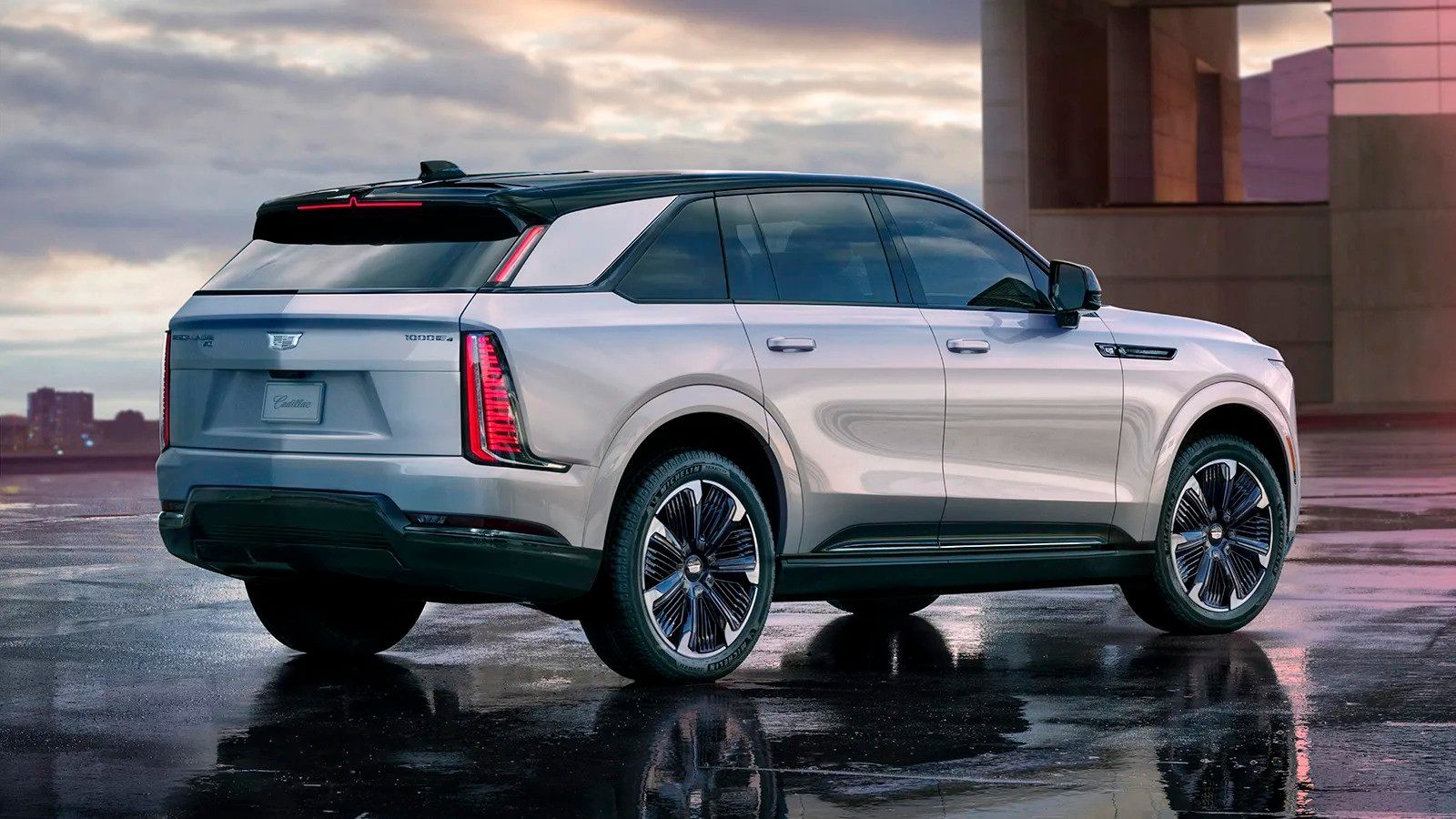 Silver SUV parked on a wet rooftop at sunset, with a city skyline in the background
