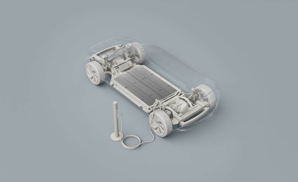 White car chassis with four wheels and a battery beside it on a gray background