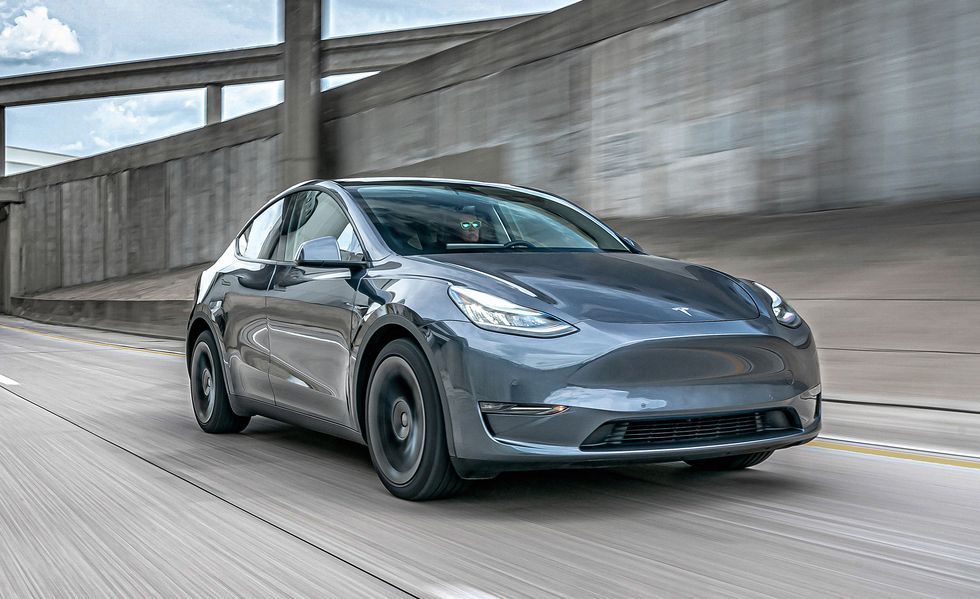 Gray Tesla sedan driving on a highway beside a concrete overpass