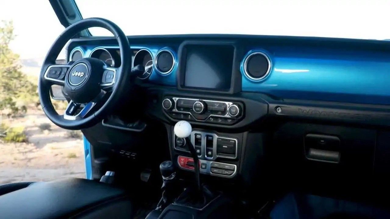 Blue car dashboard and steering wheel with a manual gear shifter and central console view