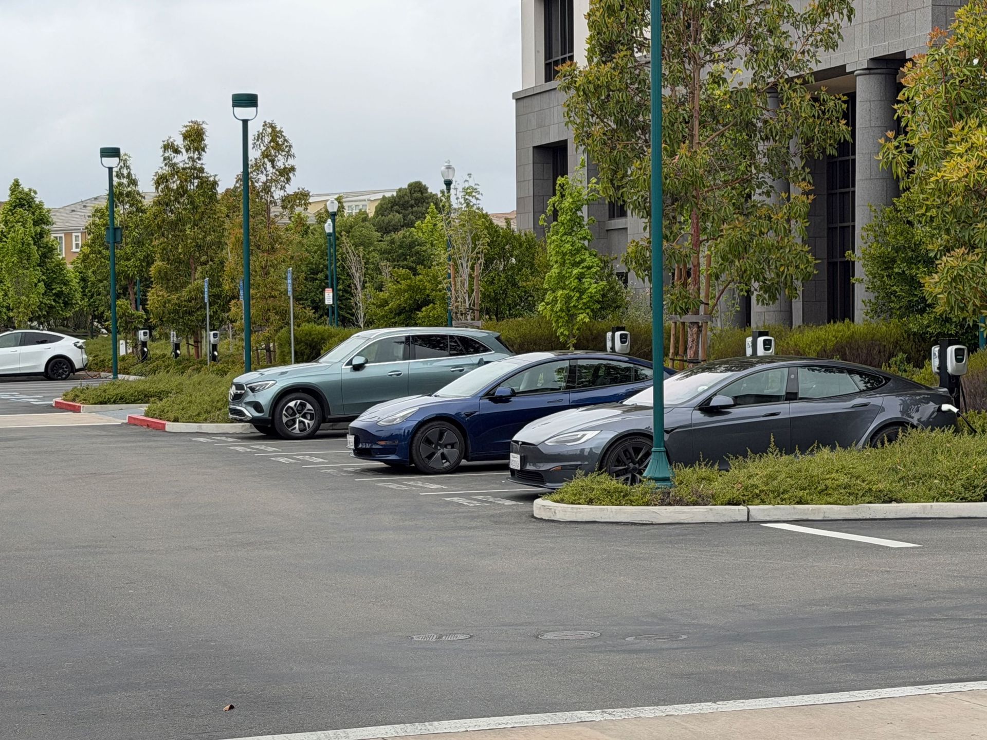 Parking lot with several parked cars beside a modern building and trees
