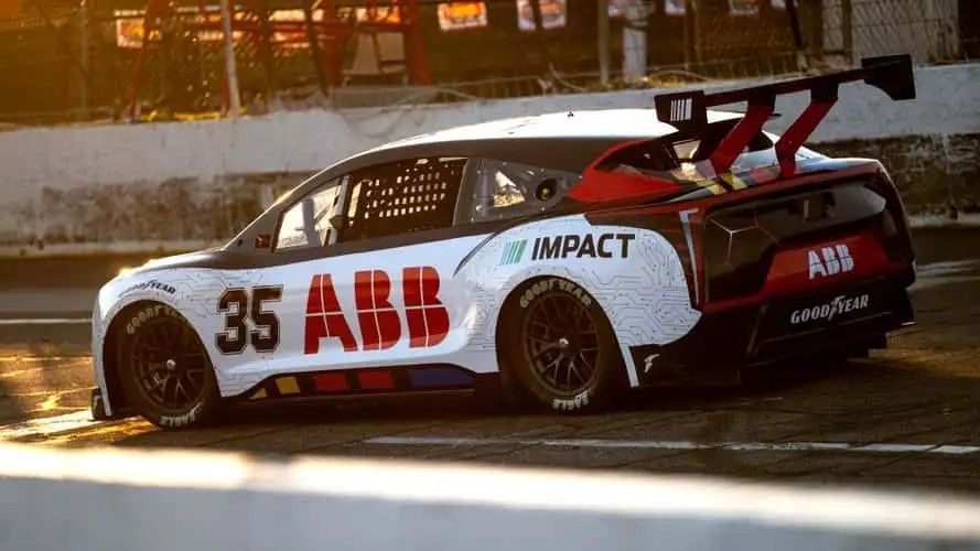 White-and-red ABB race car number 35 drifting on a sunlit track at sunset.