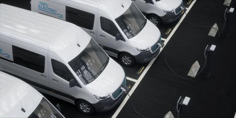 White delivery vans parked diagonally in a lot beside dark loading bays