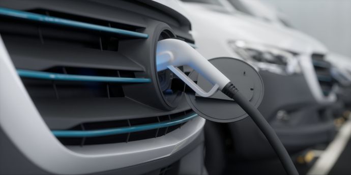 Electric car charging cable plugged into the front grille of a gray vehicle