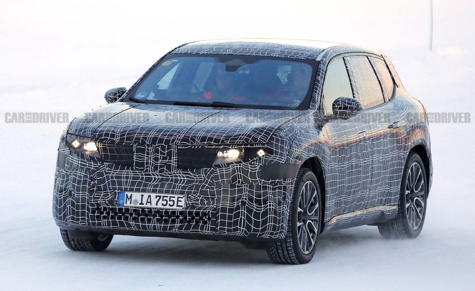 Camouflaged BMW SUV prototype driving in snowy conditions