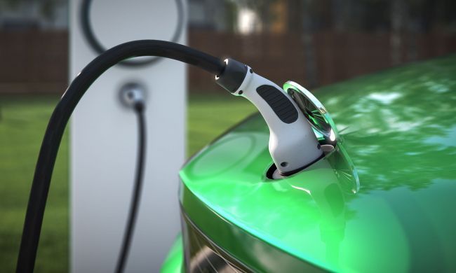 EV charging plug connected to a bright green car at a station