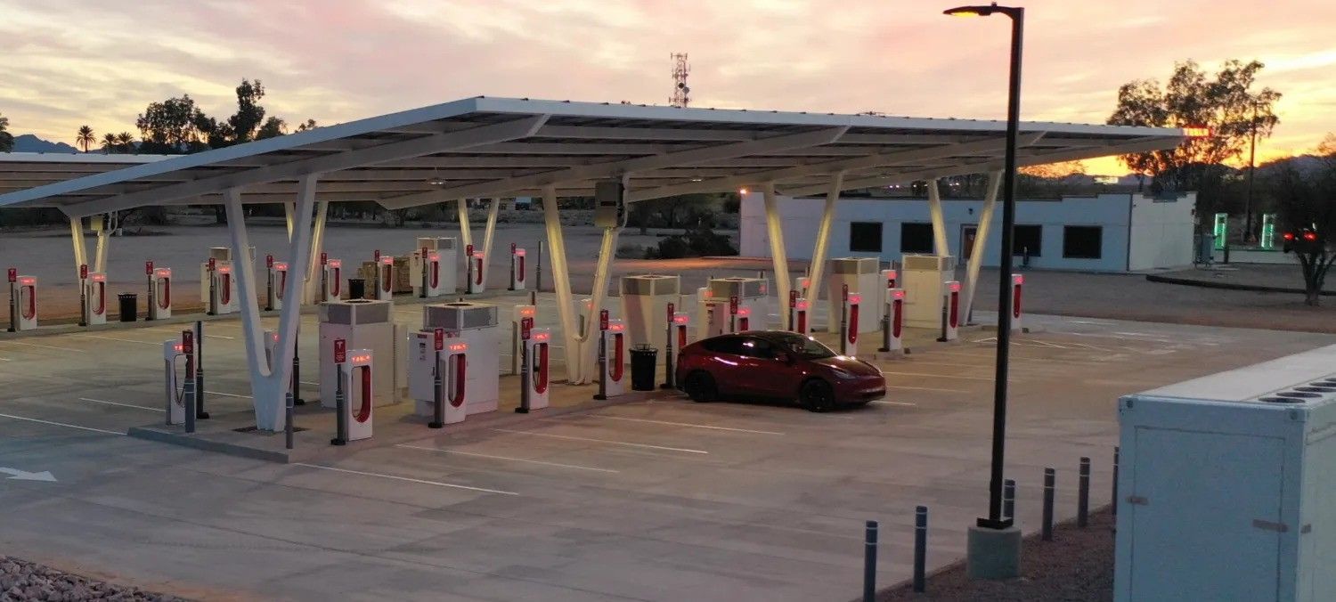 Gas station canopy at dusk with a red car stopped at the pumps