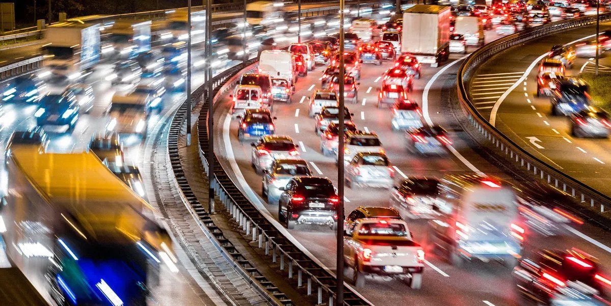Night highway traffic jam with blurred cars and red tail lights on curving roads