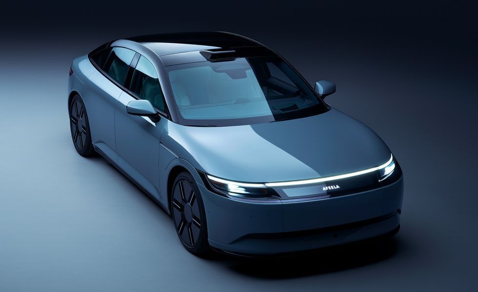 Sleek blue futuristic sedan on a dark studio background, viewed from the front-left angle