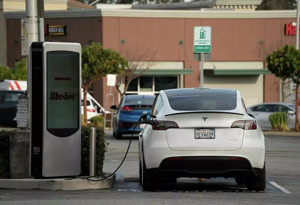 White Tesla charging at a roadside station in a parking lot