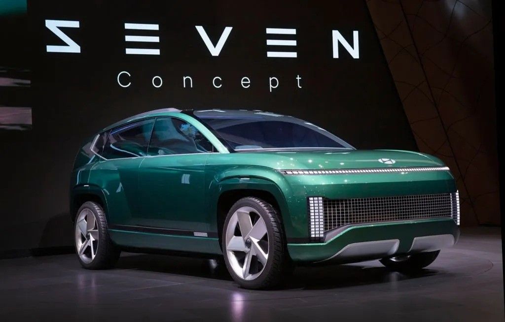 Green SEVEN Concept electric SUV on a dark showroom stage.